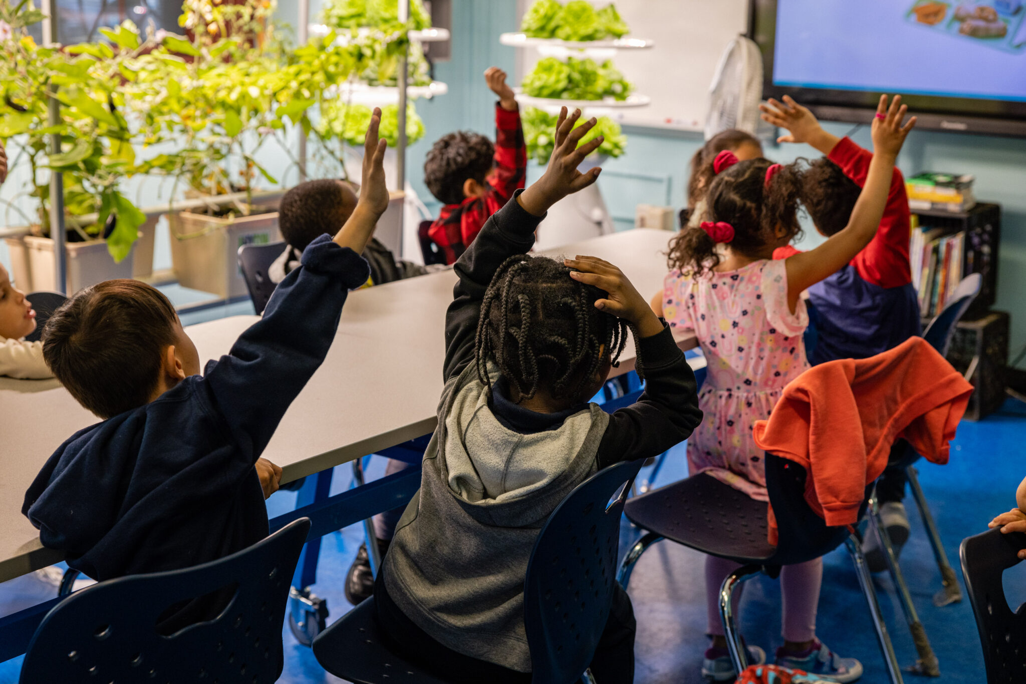 CookShop, Food Bank for New York City, MS 108, PS 108 A table of MS 108 and PS 108 K-5 public school students raise their hands during a CookShop lesson.