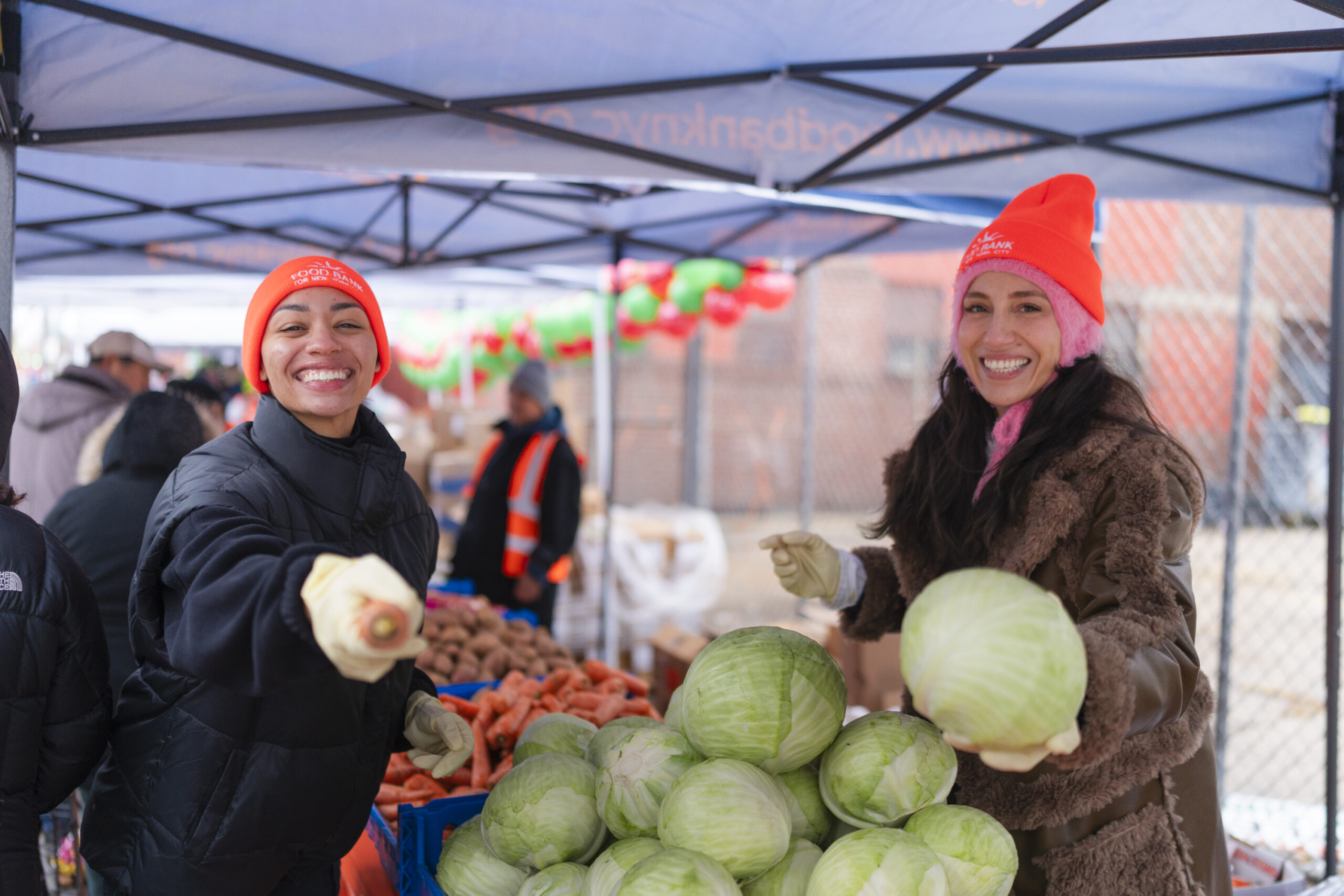 Two volunteers holding up vegetables