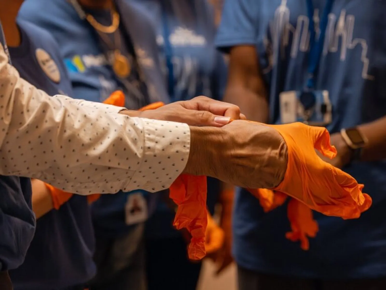 Close-up of volunteers putting on orange gloves before starting a food bank activity