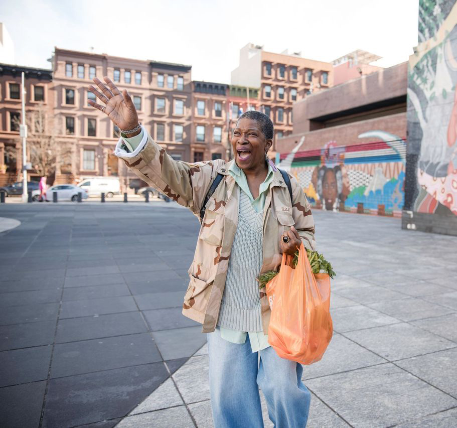 Female walking, waving and smiling while carrying groceries
