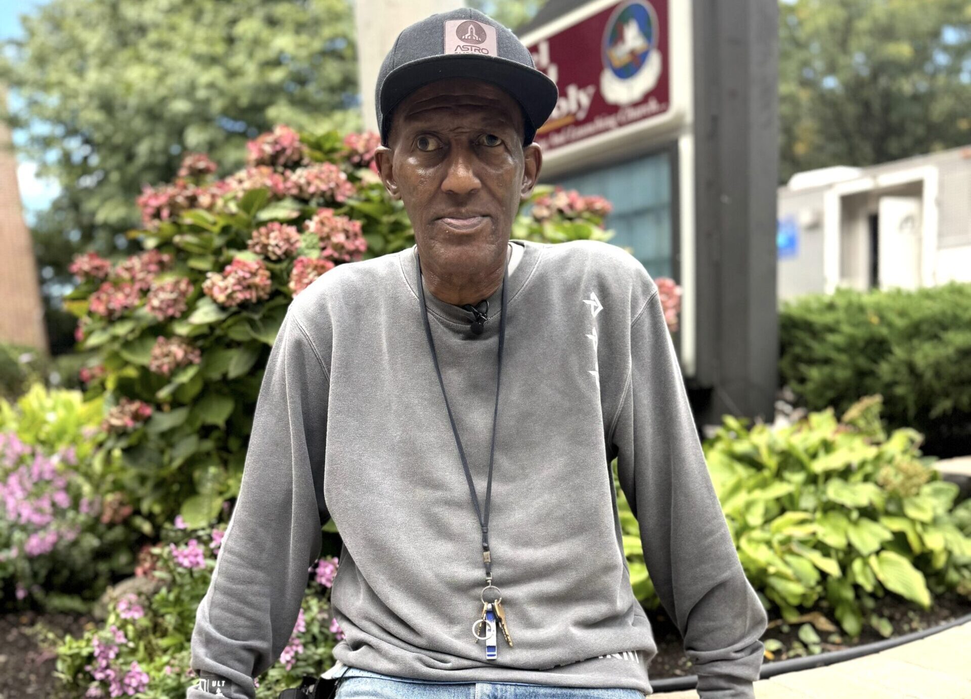 Food Bank For NYC veteran volunteer Darryl leans against the edge of a floral display in front of his apartment building.