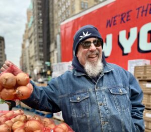 Food Bank For NYC volunteer holds bag of four onions during Downtown Brooklyn distribution.