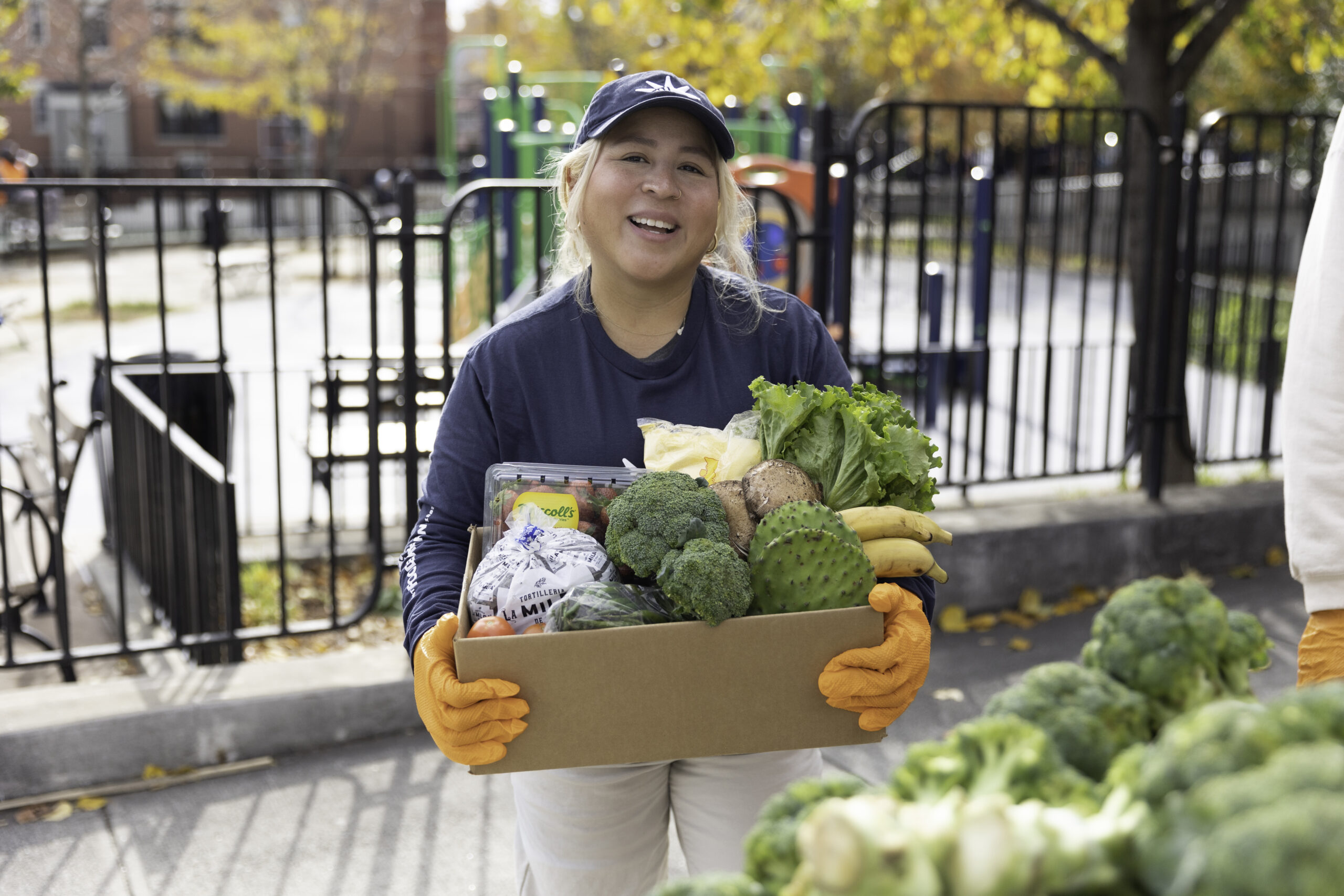 Melissa Pino smiles while holding an open box of vegetables at a fall Mobile Pantry distribution.