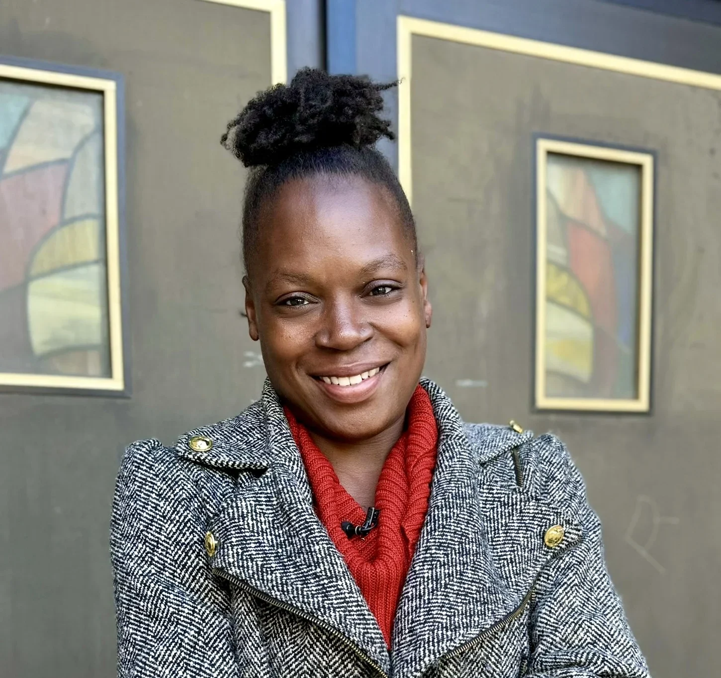 Monique, a former educator, stands smiling with arms folded.